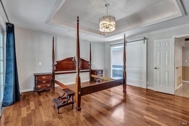 bedroom featuring a chandelier, a raised ceiling, crown molding, and wood finished floors