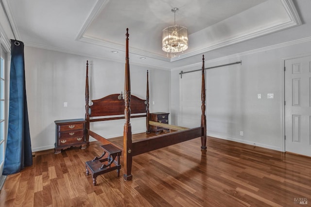 bedroom with a notable chandelier, crown molding, a raised ceiling, wood finished floors, and baseboards