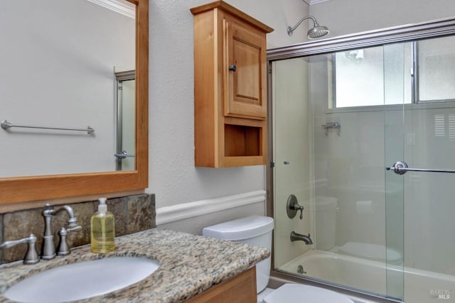 bathroom with toilet, shower / bath combination with glass door, and vanity