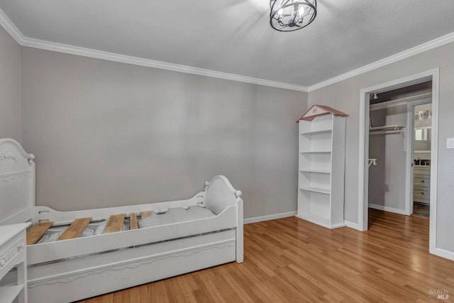 bedroom with baseboards, a notable chandelier, wood finished floors, and crown molding