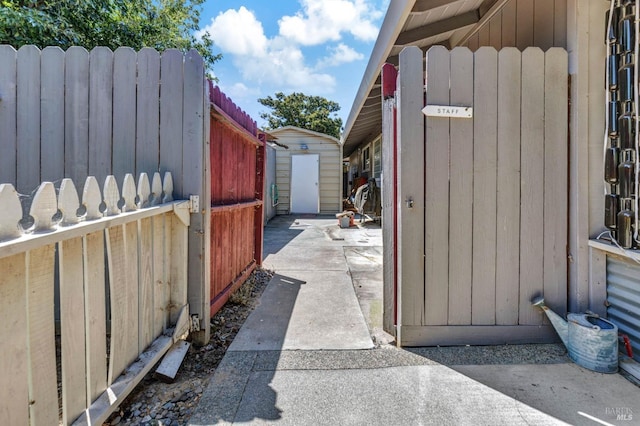 view of gate featuring a shed, fence, and an outdoor structure