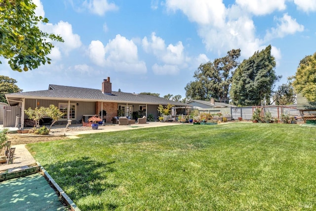 rear view of property featuring a chimney, fence, a lawn, and a patio