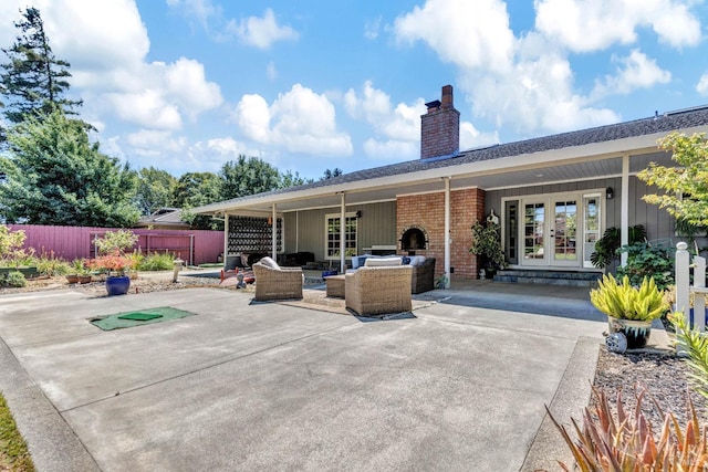 rear view of house featuring a chimney, fence, french doors, outdoor lounge area, and brick siding