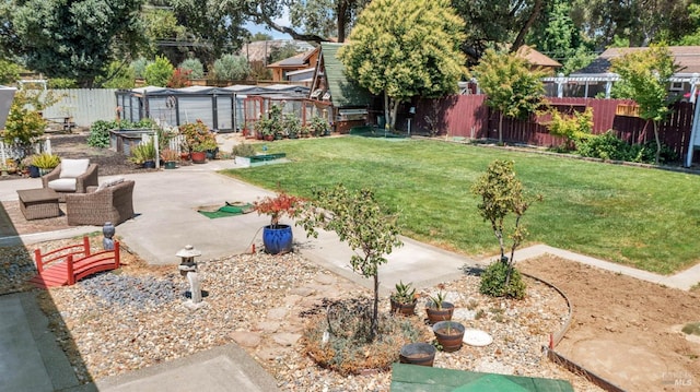 view of yard featuring an outdoor structure, a patio area, a fenced backyard, and a garden