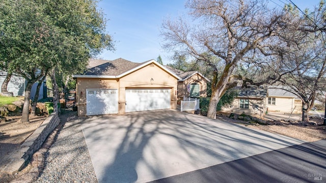 ranch-style home featuring driveway, an attached garage, and stucco siding