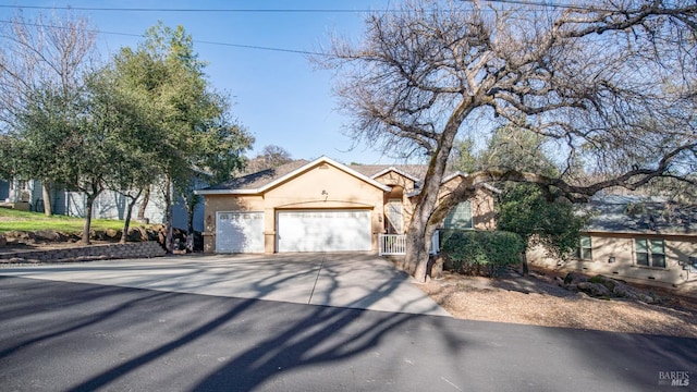 view of front facade with an attached garage, driveway, and stucco siding