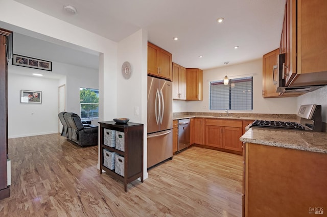 kitchen featuring light stone countertops, appliances with stainless steel finishes, sink, and light hardwood / wood-style flooring