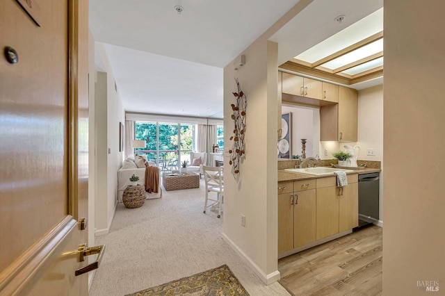 interior space featuring sink, dishwasher, a skylight, light colored carpet, and light brown cabinets