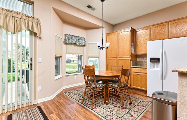 dining space with visible vents, a notable chandelier, baseboards, and wood finished floors