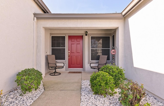 view of exterior entry with a porch and stucco siding