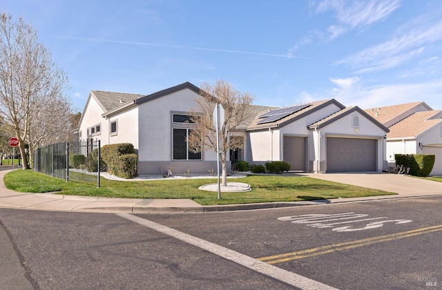 ranch-style home with a garage, solar panels, fence, stucco siding, and a front yard