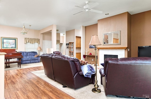 living area with a fireplace, light wood-style flooring, and a ceiling fan