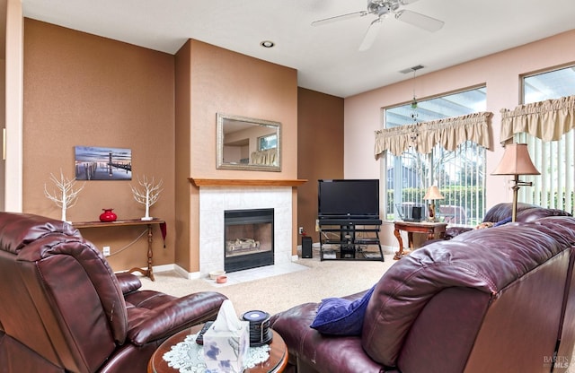 carpeted living area featuring baseboards, ceiling fan, visible vents, and a tiled fireplace