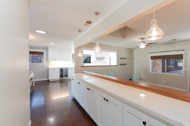 kitchen featuring white cabinetry, beverage cooler, decorative light fixtures, and dark hardwood / wood-style flooring