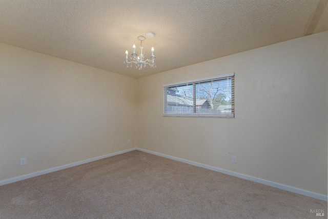 spare room featuring carpet floors, a textured ceiling, and an inviting chandelier