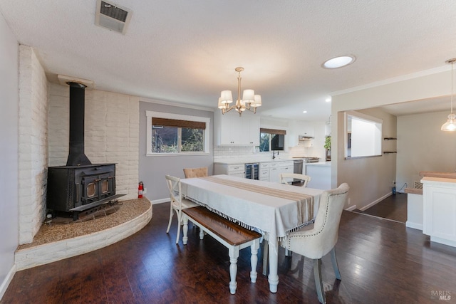 dining space with wine cooler, a textured ceiling, a wood stove, ornamental molding, and dark hardwood / wood-style flooring