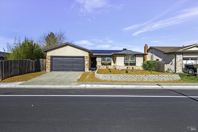 ranch-style house featuring a garage and solar panels