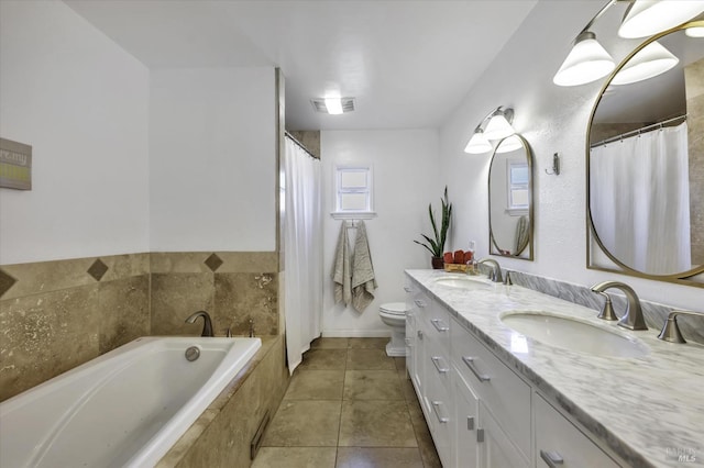 bathroom with tile patterned flooring, tiled tub, vanity, and toilet