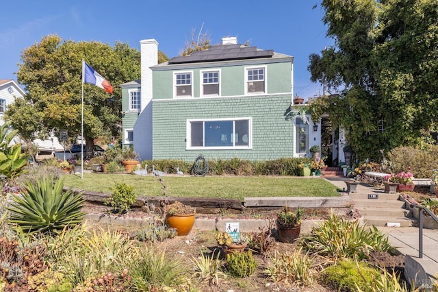 view of front of property with a front lawn and solar panels