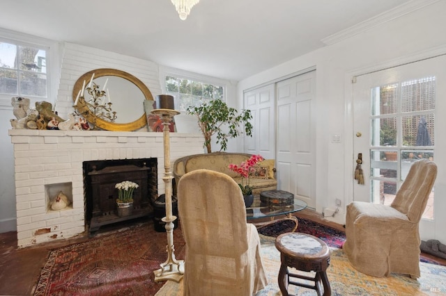 living area featuring crown molding, a healthy amount of sunlight, and a brick fireplace