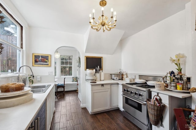 kitchen with pendant lighting, sink, high end stainless steel range oven, a notable chandelier, and dark wood-type flooring