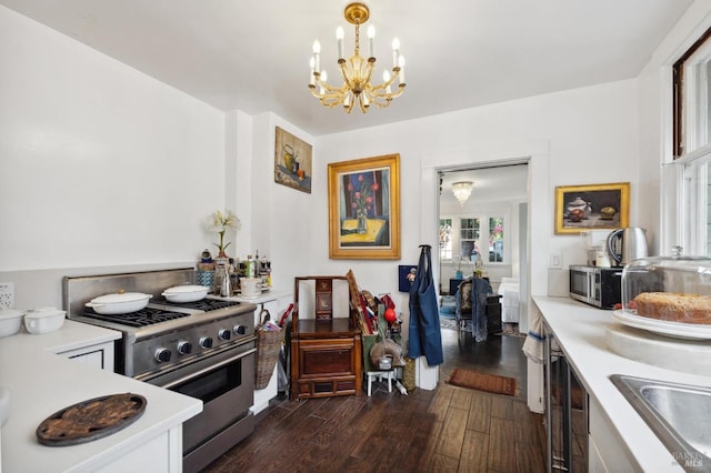 kitchen with appliances with stainless steel finishes, decorative light fixtures, sink, dark wood-type flooring, and an inviting chandelier