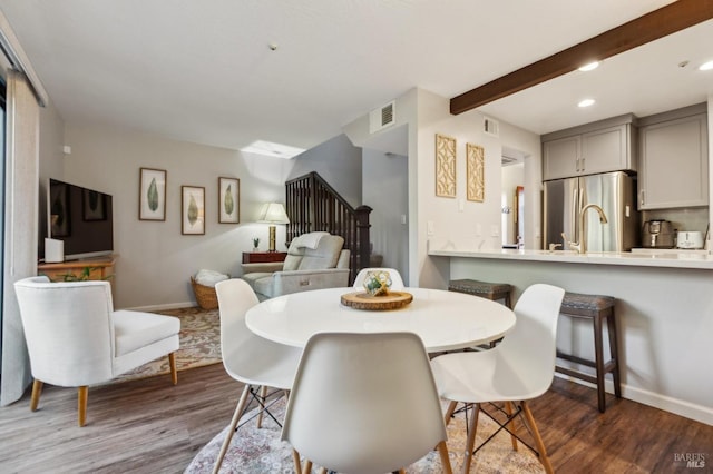 dining room featuring baseboards, visible vents, dark wood-type flooring, and beamed ceiling