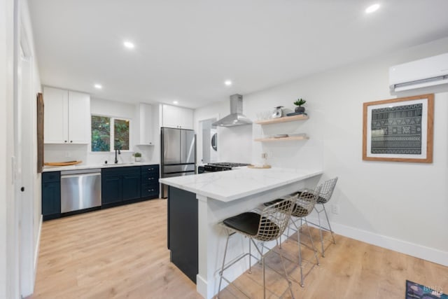 kitchen featuring a breakfast bar area, appliances with stainless steel finishes, white cabinetry, ventilation hood, and kitchen peninsula