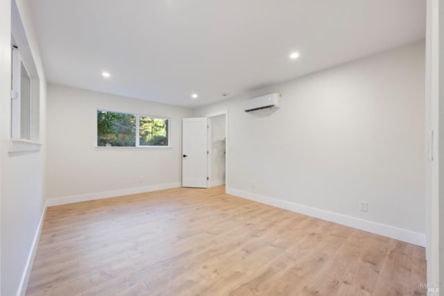 spare room with a wall mounted AC and light wood-type flooring