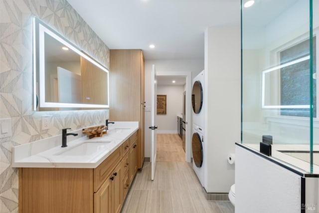 bathroom featuring vanity, stacked washer / drying machine, and toilet