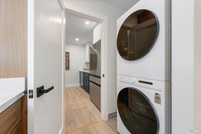 laundry area featuring stacked washer / dryer and light hardwood / wood-style floors