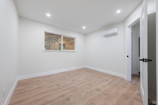 spare room with a wall mounted AC and light hardwood / wood-style flooring