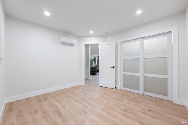 spare room with a wall unit AC and light hardwood / wood-style floors