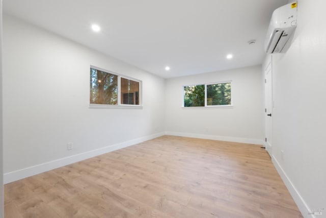 spare room featuring a wall mounted air conditioner and light hardwood / wood-style flooring