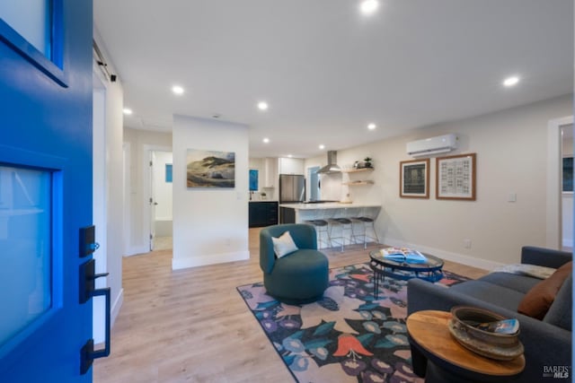 living room featuring a wall mounted air conditioner, a barn door, and light wood-type flooring