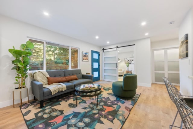 living room with a barn door and light wood-type flooring