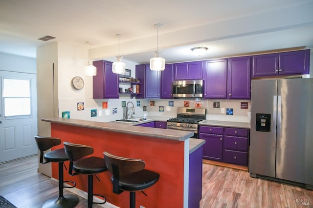 kitchen featuring appliances with stainless steel finishes, a breakfast bar, sink, kitchen peninsula, and light wood-type flooring