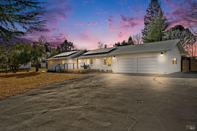 view of front of house featuring an attached garage, driveway, and roof mounted solar panels