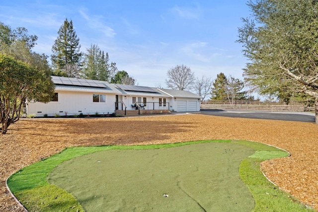 view of front of home with solar panels, crawl space, an attached garage, and fence