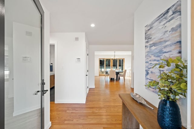 hallway featuring a notable chandelier, recessed lighting, baseboards, and light wood-style floors