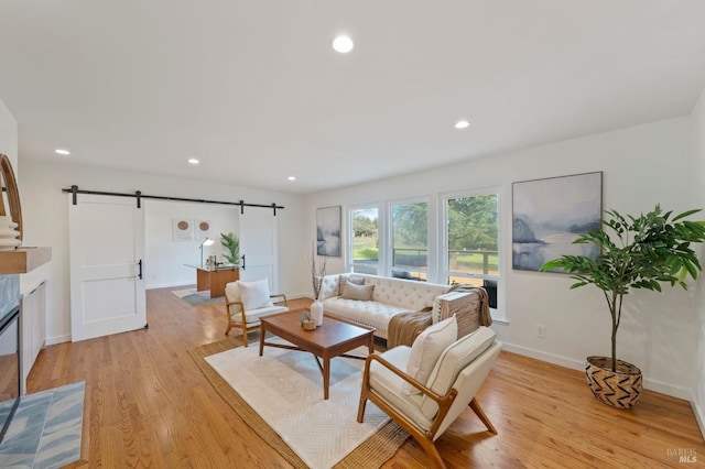 living room featuring a barn door, baseboards, light wood-style flooring, and recessed lighting