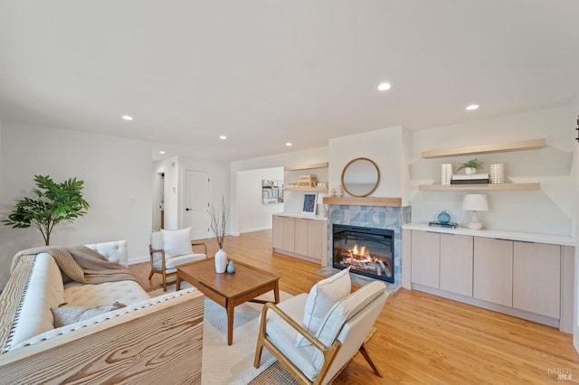 living room featuring baseboards, a tile fireplace, light wood-style flooring, and recessed lighting