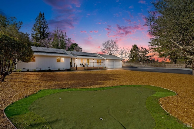 rear view of property featuring a garage, crawl space, fence, and roof mounted solar panels