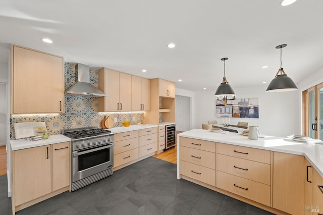 kitchen featuring wall chimney exhaust hood, hanging light fixtures, light countertops, stainless steel stove, and light brown cabinets