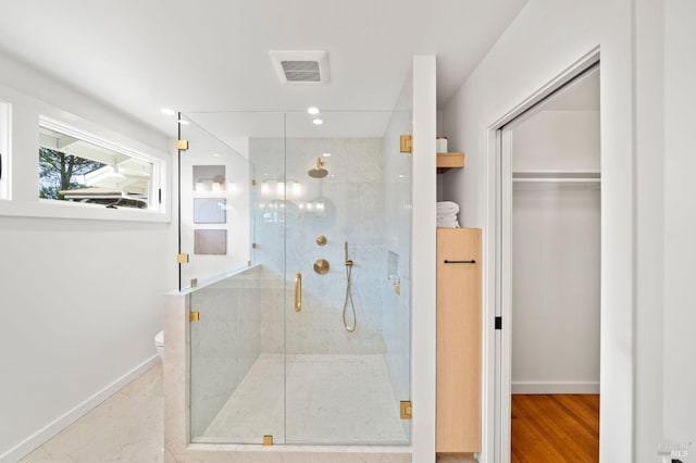 full bath with visible vents, baseboards, a walk in closet, a shower stall, and recessed lighting