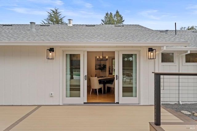 view of exterior entry with roof with shingles