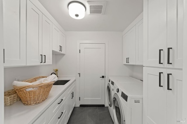 washroom featuring dark tile patterned flooring, cabinet space, visible vents, and washing machine and clothes dryer