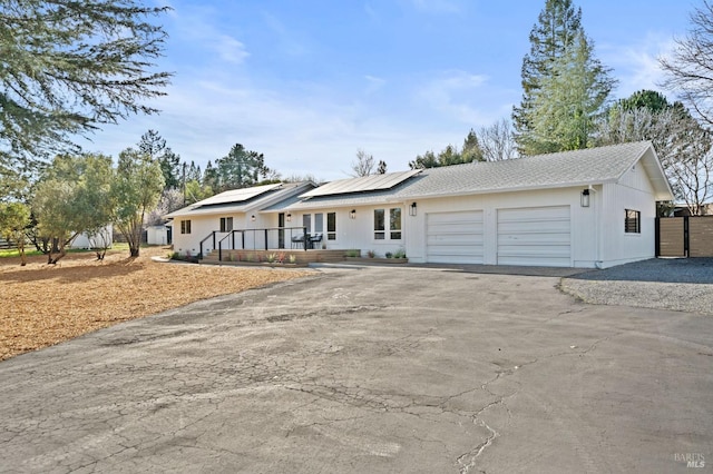 single story home with solar panels, aphalt driveway, and an attached garage