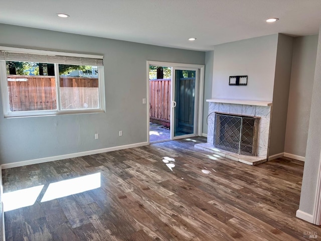 unfurnished living room featuring a tiled fireplace and hardwood / wood-style flooring