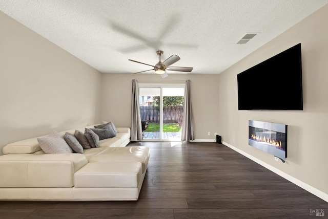 living room with dark hardwood / wood-style flooring, a textured ceiling, and ceiling fan